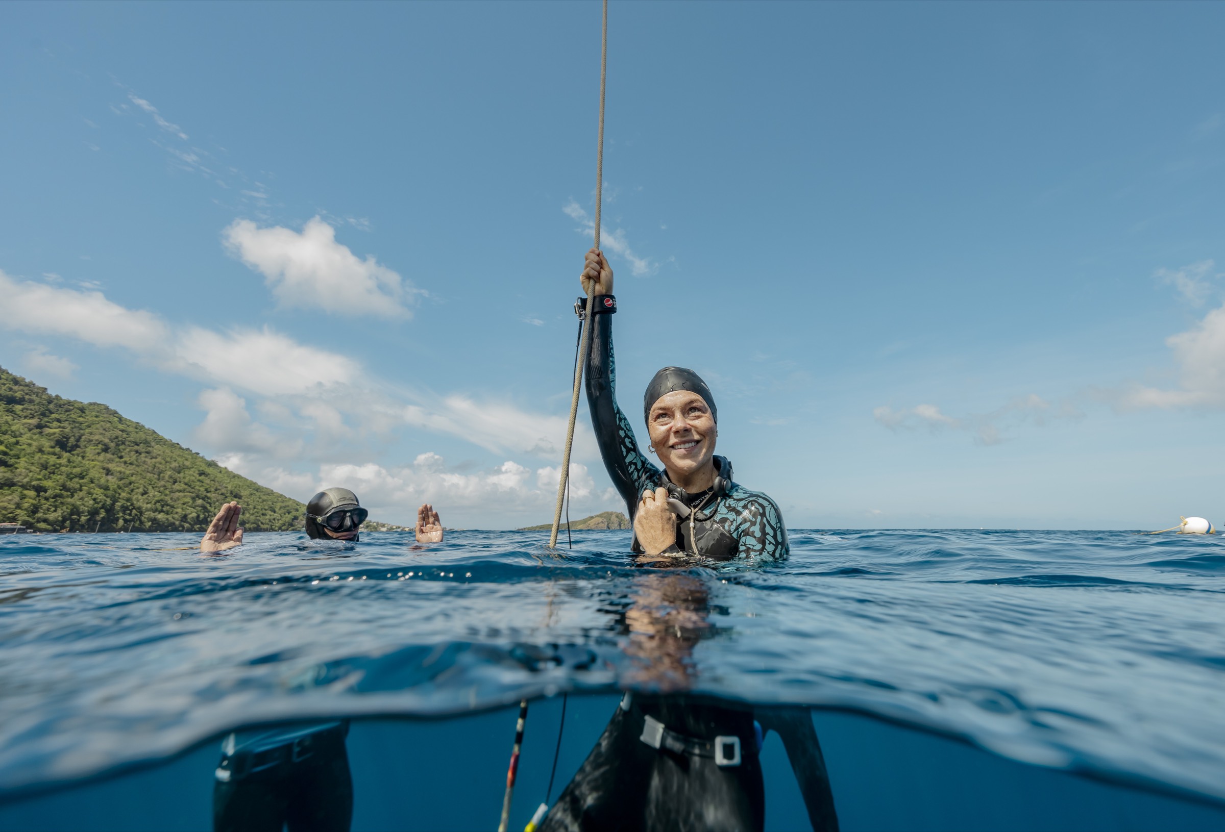 Natalie Bruce surfacing after a competition dive with safety divers nearby